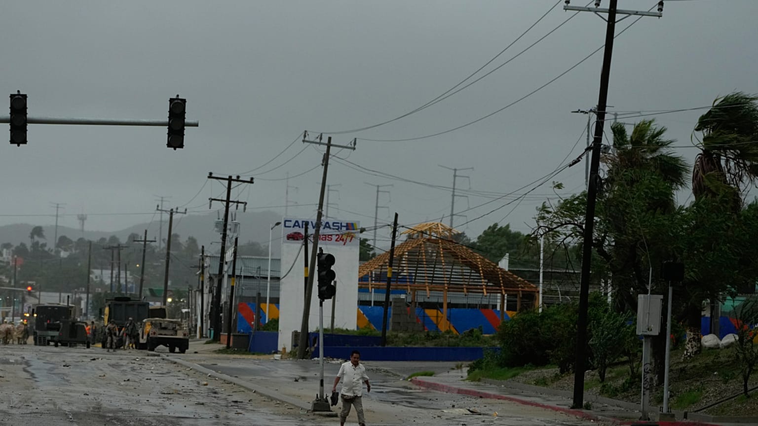 Un hombre sin zapatos camina cerca de una avenida inundada por las lluvias del huracán Norma en San José del Cabo, México.