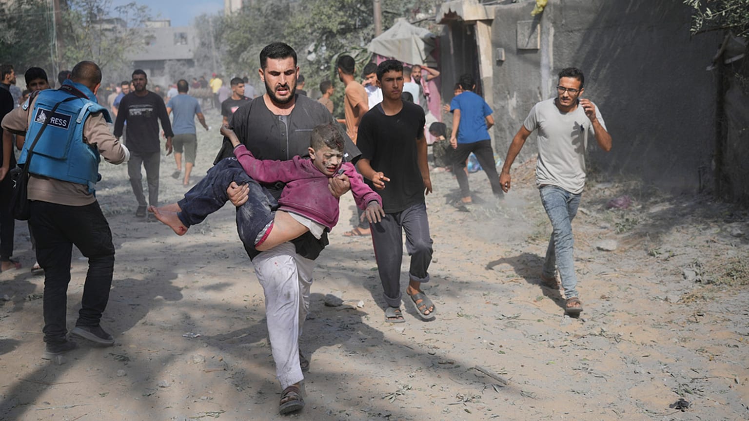 Homem palestiniano transporta rapaz ferido durante bombardeamento de Israel à Faixa de Gaza