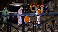 Belgian police officers from the forensic service search for evidence in a street after two people were killed during a shooting in Brussels on October 16, 2023.