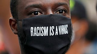 FILE - A protester wears a face mask in front of the US embassy, during the Black Lives Matter protest rally in London, Sunday, June 7, 2020.