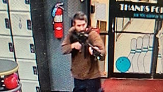 O atirador empunhando a arma à entrada no salão de "nowling"