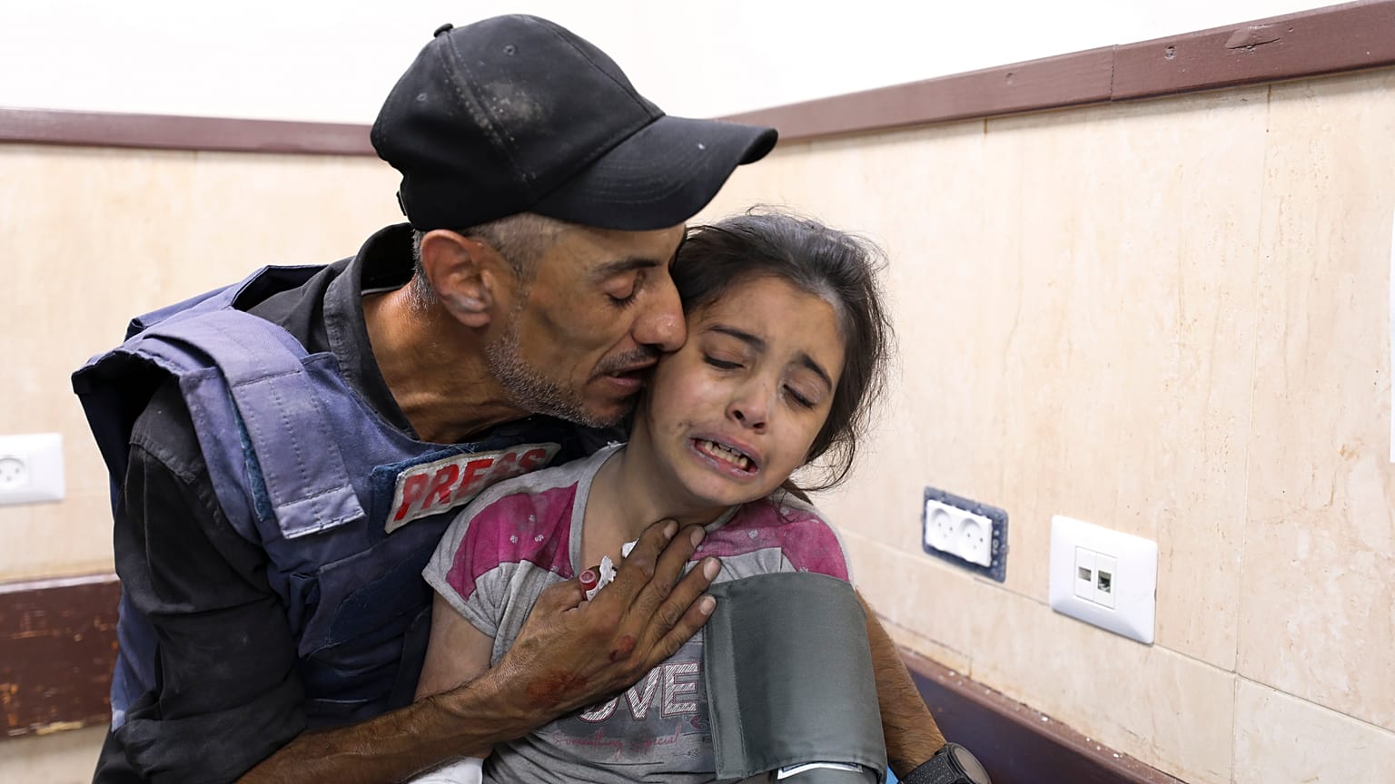 صحفي فلسطيني يواسي ابنة أخيه التي أصيبت في غارة إسرائيلية على منزل عائلتها في مخيم النصيرات للاجئين