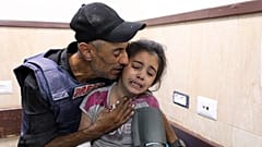 صحفي فلسطيني يواسي ابنة أخيه التي أصيبت في غارة إسرائيلية على منزل عائلتها في مخيم النصيرات للاجئين