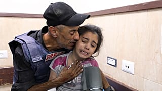 صحفي فلسطيني يواسي ابنة أخيه التي أصيبت في غارة إسرائيلية على منزل عائلتها في مخيم النصيرات للاجئين