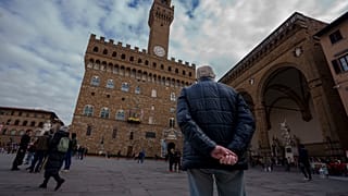 An elderly man looks at the 14th-century town hall 'Palazzo Vecchio' (Old Palace) in Florence, Italy, Thursday, Feb. 17, 2022.