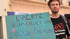 Ein französischer Vater, der Homeschooling praktiziert, während einer Demonstration am 15. September 2023 in Lyon.