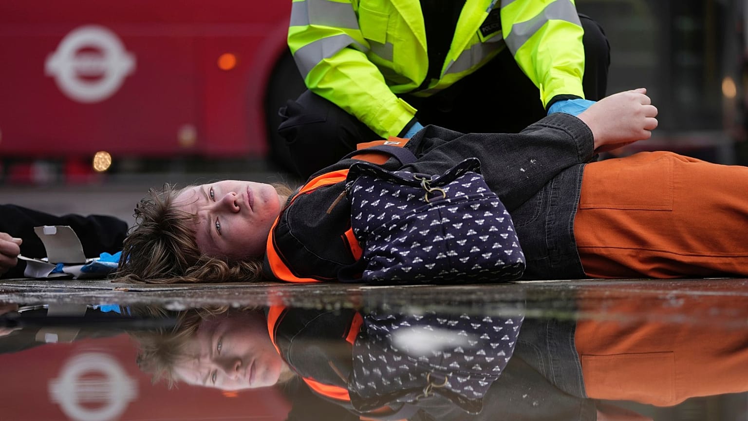 An activist from the group Just Stop Oil is arrested by police officers as they slow the traffic, marching on a road, in London, 30 October 2023. 