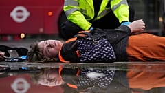 An activist from the group Just Stop Oil is arrested by police officers as they slow the traffic, marching on a road, in London, 30 October 2023. 