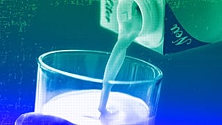 A person pours milk into a glass