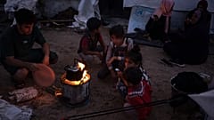 فلسطينيون نزحوا بسبب القصف الإسرائيلي يجلسون بجوار النار في مخيم بخان يونس