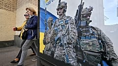 Pedestrians walk past a poster depicting Ukrainian servicemen and a slogan which reads "Bring the victory soon" in Kyiv, on 31 October