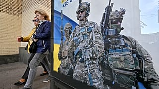 Pedestrians walk past a poster depicting Ukrainian servicemen and a slogan which reads "Bring the victory soon" in Kyiv, on 31 October