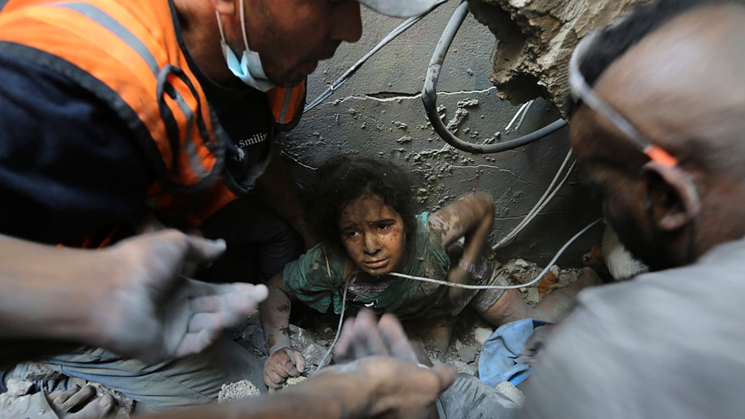 Palestinianos tentam tirar uma menina dos escombros de edifício destruído pelos ataques de Israel ao campo de refugiados de Jabalia, na Faixa de Gaza