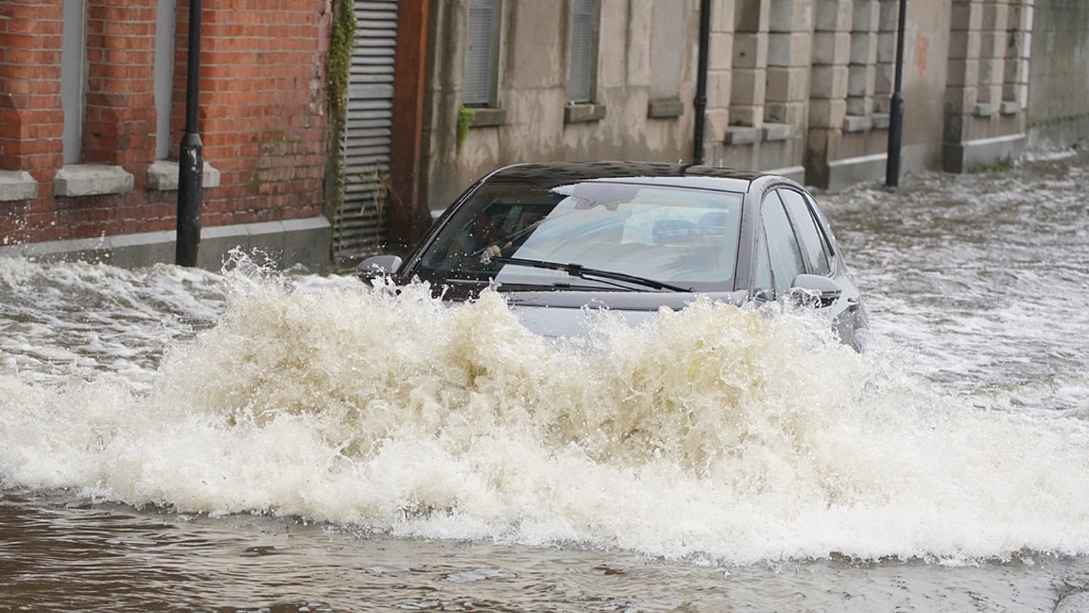 A car drives through flood water on Canal Quay in Newry Town, Co Down, which has been swamped by floodwater as the city's canal burst its banks amid heavy rainfall.