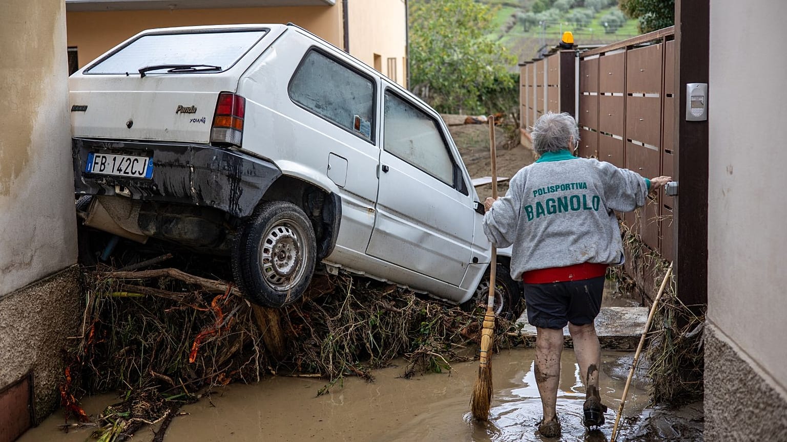 A woman tries to clean the mud in Montemurlo near Prato after heavy rain last night, on November 3, 2023. 