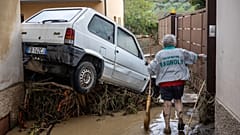 A woman tries to clean the mud in Montemurlo near Prato after heavy rain last night, on November 3, 2023. 