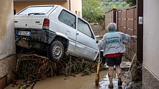 A woman tries to clean the mud in Montemurlo near Prato after heavy rain last night, on November 3, 2023. 