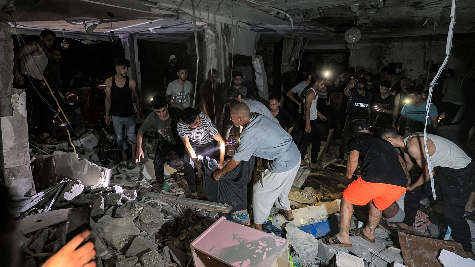 رجال الإنقاذ والناس يفتشون منزل الصحفي في تلفزيون فلسطين محمد أبو حطب