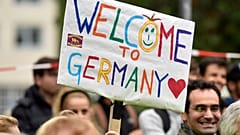 Menschen begrüßen Flüchtlinge mit einem Transparent mit der Aufschrift "Willkommen in Deutschland" in Dortmund, Deutschland, Sonntag, 6\. September 2015.