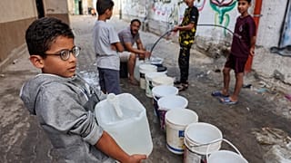 Um menino carrega um garrafão com água, em Gaza, 01 de novembro 2023