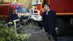 France's President Emmanuel Macron (R) speaks with a firefighter during a visit in a region hit by Storm Ciaran in Plougastel-Daoulas, western France