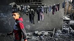 Ein Junge sieht zu, wie Menschen in Gebäuden, die während der israelischen Bombardierung zerstört wurden, nach Überlebenden und den Leichen von Opfern suchen, in Al-Maghazi, Gazastreifen, am Sonntag