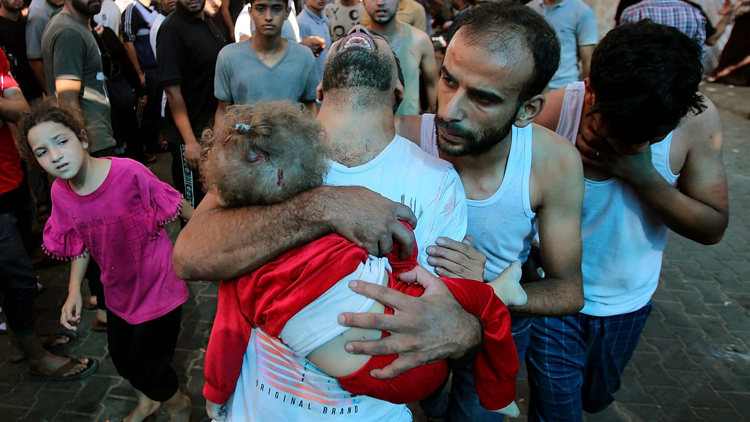أب فلسطيني يحمل طفلاً صغيرًا إلى مستشفى الشفاء عقب قصف الجيش الإسرائيلي لمنزل في حي المنصورة بمدينة غزة.