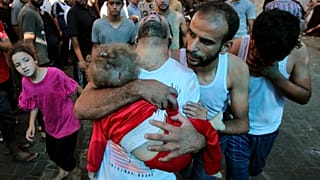 أب فلسطيني يحمل طفلاً صغيرًا إلى مستشفى الشفاء عقب قصف الجيش الإسرائيلي لمنزل في حي المنصورة بمدينة غزة.