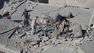 Palestinianos procuram sobreviventes após bombardeamento edo campo de Nusseirat, em Gaza