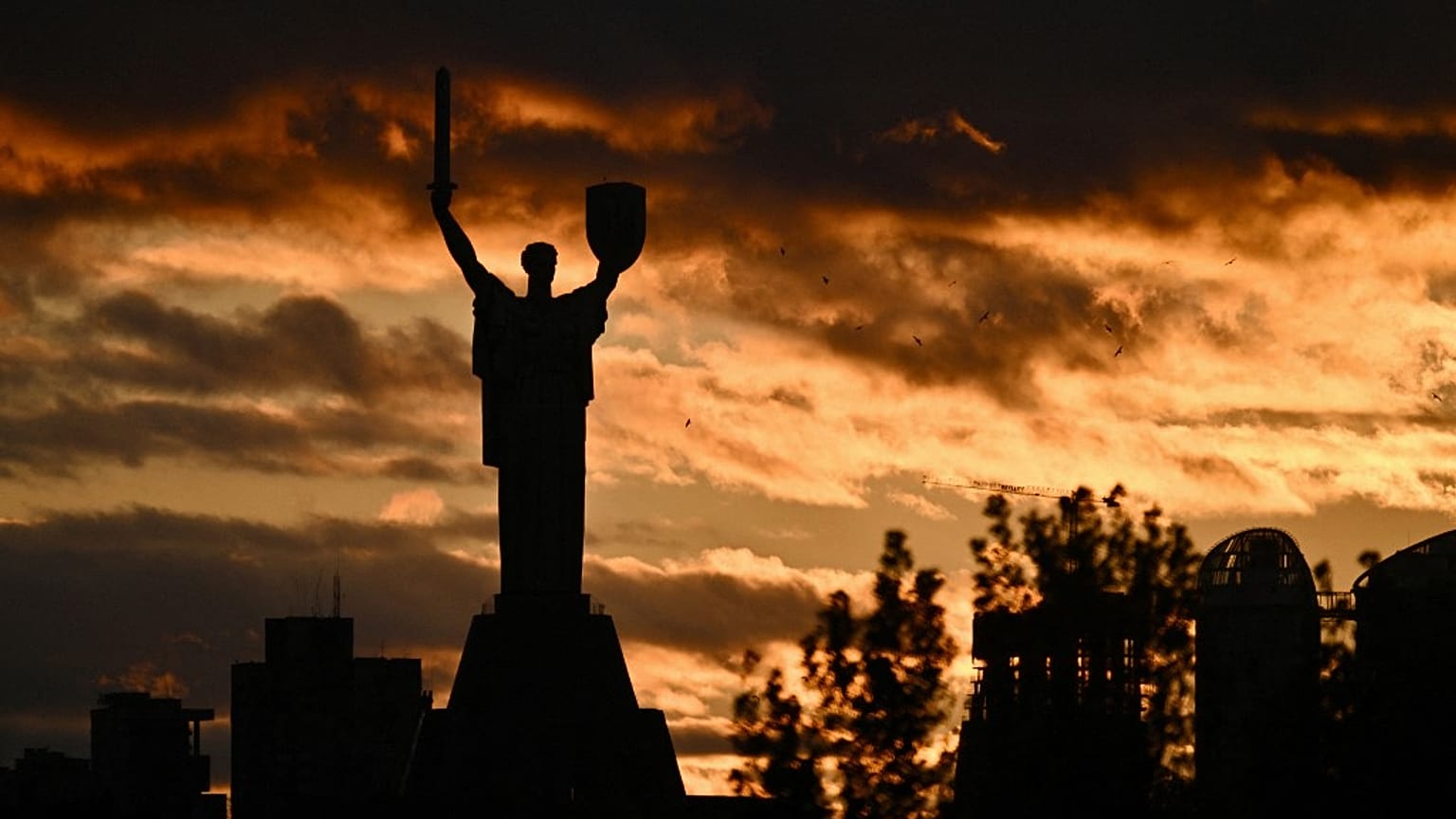 A photograph shows the Motherland monument silhouetted against a cloudy sky at sunset in Kyiv on October 28, 2023.