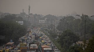 A pedestrian walks on a bridge above vehicle traffic in New Delhi, India