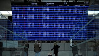 Ταξιδιώτες κοιτάζουν τον πίνακα πληροφοριών αναχώρησης του αεροδρομίου Charles de Gaulle