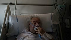 A COVID-19 patient adjusts his oxygen mask as he receives treatment in the Hospital del Mar in Barcelona, Spain, 2021.