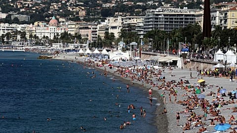 Not much snow: People sunbathing and swimm in long pebble beach of Carras in downtown Nice on the French Riviera