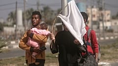 فلسطيني وزوجته على طريق النزوح من شمال غزة باتجاه الجنوب ورفع راية بيضاء اتقاء للقصف الإسرائيلي  