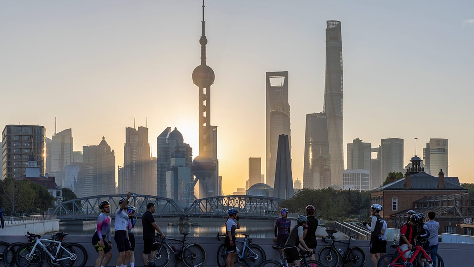 Cyclists, some take selfie as they take rest against the sunrise skylines in Pudong, China's financial and commercial hub, in Shanghai, China on Friday, Nov. 3, 2023.