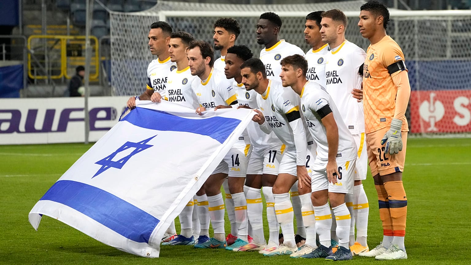 لاعبو مكابي تل أبيب يرفعون العلم الإسرائيلي  قبل مباراة كرة القدم بين زوريا لوهانسك ومكابي تل أبيب في المجموعة ب من دوري أوروبا للمؤتمرات في ملعب أرينا لوبلين في بولندا