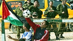 FILE: Israeli soldiers, background, watch as Palestinians and foreign activists play at the construction site of Israel's separation barrier in the village of Bil'in. 