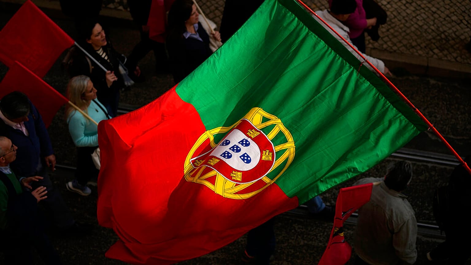 A Portuguese flag is carried among people in Lisbon protesting the rising cost of living, Thursday, Feb. 9, 2023. 