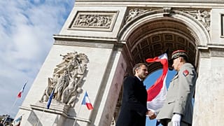 French President Emmanuel Macron shakes hands with FMilitary Governor of Paris and Army Corps General Christophe Abad (R) after a ceremony at the Tomb of the Unknown Soldier