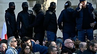 Spectators wearing face-coverings join the crowds waiting to view the two minute's silence near to the Cenotaph on Whitehall in central London