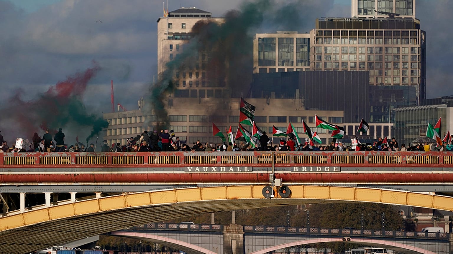 Protesters wave flags and hold flares during a pro-Palestinian protest in London, Saturday, Nov. 11, 2023.