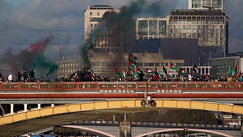 Protesters wave flags and hold flares during a pro-Palestinian protest in London, Saturday, Nov. 11, 2023.