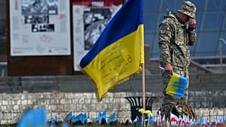 A serviceman mourns next to a Ukrainian flag at a makeshift memorial for fallen soldiers at Independence Square in Kyiv