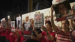 Various pictures of women holding pictures of hostages held by Hamas.