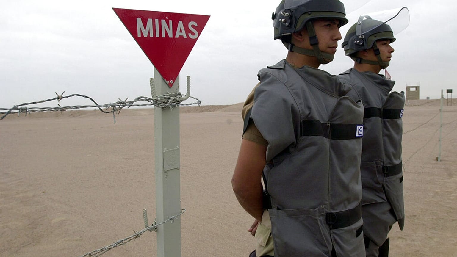 Dos soldados custodian la entrada a una zona delimitada en la que se llevan a cabo labores de desminado. 