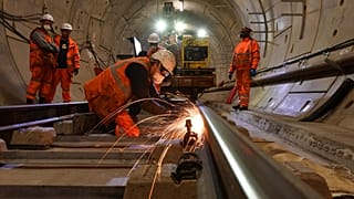 Construction workers work on a section of train track inside a Crossrail tunnel, beneath Stepney in east London on November 16, 2016. 