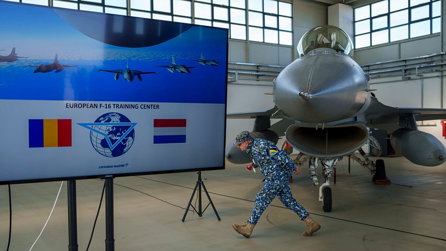 Un militaire roumain devant un F-16 de la Royal Dutch Air Force dans un hangar de la base aérienne militaire de Baza 86, à l'extérieur de Fetesti, en Roumanie, novembre 2023