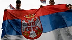 Молодые сербы держат флаг Сербии в Косове