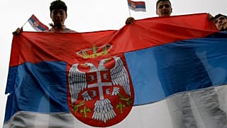 Молодые сербы держат флаг Сербии в Косове
